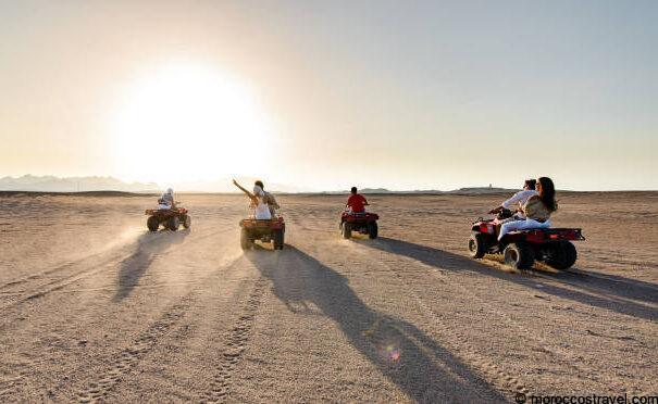 Moto Quad Bike Excursions & Tours In Desert - Merzouga Back view of group of people driving quad bikes in the desert at sunrise. Copy space.